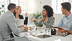 Young mixed race businesswoman with a curly afro explaining an idea in a meeting at work. Group of businesspeople having a meeting together at a table. Business professionals talking and planning in an office