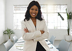Young happy african american businesswoman standing with her arms crossed while in an office alone. One confident black female boss smiling and standing at work