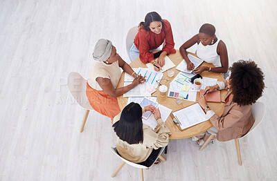 Buy stock photo Above view of diverse group of business women having a brainstorm meeting in office with copyspace. Confident professional team sitting together and using paperwork while planning a marketing strategy