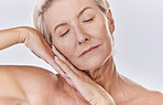 One mature caucasian woman relaxing with a hand on her face against a pink background. Peaceful senior woman resting, caring for her skin while doing a skincare routine