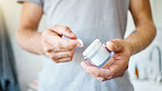 An unknown man applying cream or moisturiser to his face in a bathroom at home. One unrecognizable male using a lotion or sunscreen in his apartment