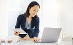 Focused young asian businesswoman using a digital tablet device and laptop while planning notes at a desk in an office. One female only browsing online while planning research documents and reviewing data. Lawyer compiling legal reports