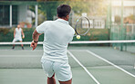 Two ethnic tennis players holding rackets and playing court game. Rear view of unknown team of athletes together during match. Playing competitive doubles match for fitness and health in sports club
