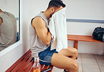 Young player wiping his face with a towel. Tired man cleaning his face with a towel after a squash match. Squatch player sitting in his gym locker room. Mixed race man taking a break after a match