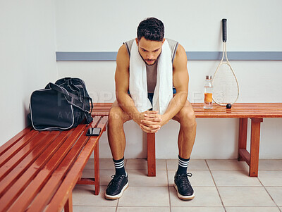 Buy stock photo Young player sitting on a bench in his locker room. Serious mixed race player preparing for a squash match in his gym. Focused squash player relaxing in his gym locker room alone