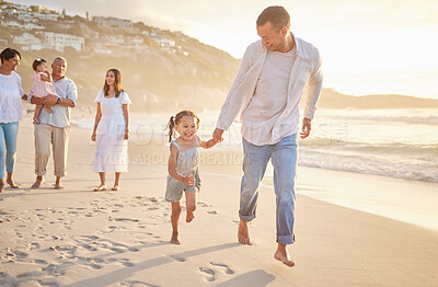 Buy stock photo Cute little girl running hand in hand with her mixed race dad on the beach. A daughter and her father holding hands while playing in the sand next to the sea at sunset. Family bonding at the coast