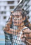 Close up of a female athlete leaning against a tennis net. Young hispanic tennis player posing on a tennis court