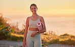 Portrait of yoga woman holding yoga mat after outdoor practice in remote nature at sunset. Beautiful smiling young caucasian standing alone. One happy person feeling cheerful, content, zen and mindful