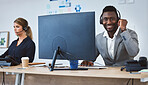 Portrait of happy young african american call centre telemarketing agent talking on a headset while working on computer alongside a colleague in an office. Confident friendly male consultant operating helpdesk for customer service and sales support