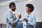 Two happy young african american call centre telemarketing agents having a chat while drinking coffee and laughing together during lunch break in an office