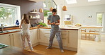 A young couple happily dancing with each other in the kitchen