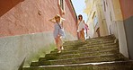 Carefree excited friends running down a set of stairs together while on holiday
