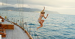 Carefree young woman in a bikini jumping from boat into the ocean. Woman on holiday jumping from a boat during a cruise to swim in the ocean. Woman sailing on a yacht jumping into the ocean to swim