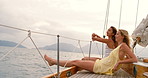Two content women enjoying a cruise sitting on a boat during a cloudy day together. Happy friends enjoying the ocean view during a yacht cruise together. Two friends enjoying a cruise together