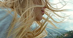 Closeup of a blonde woman with her hair blowing in her face on a windy day on a yacht. Young woman with her hair blowing in the wind around her face during a cruise