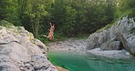Two friends excitedly jumping into a lake together to swim. Two women having fun jumping into a lake to swim. Happy women having fun swimming in a lake