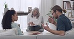 Rear view of a young interracial couple arguing during a therapy session with their mature female therapist in a office while sitting on a sofa. Unhappy boyfriend and latin girlfriend trying to resolve issues in their relationship